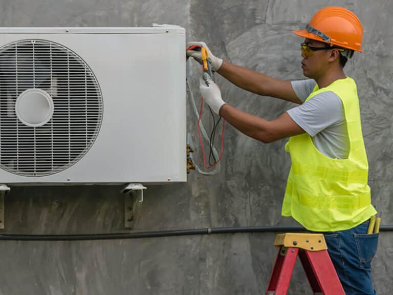HVAC technician servicing commercial air conditioning unit outdoor condenser