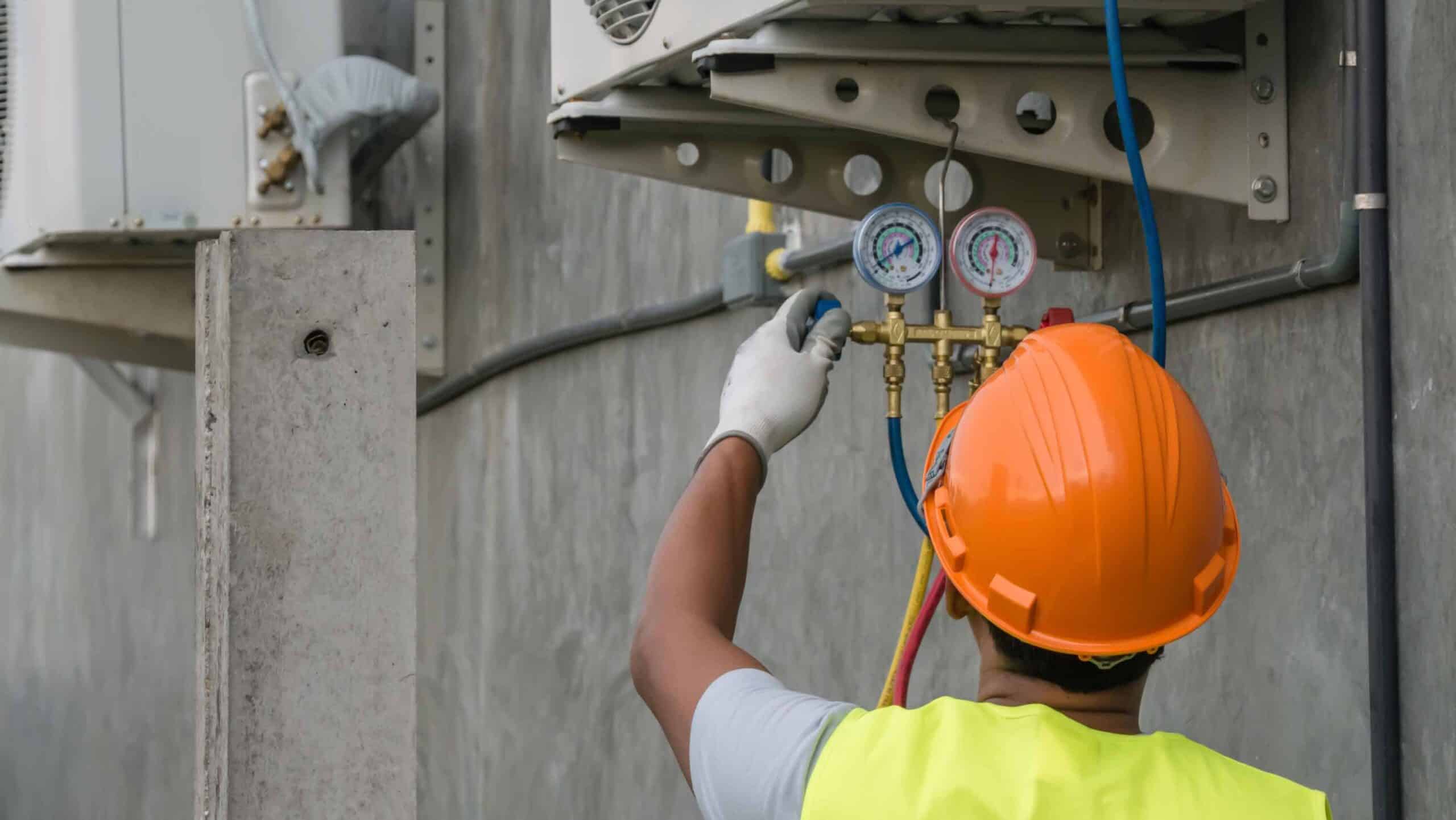 HVAC technician performing maintenance on air conditioning system gauges
