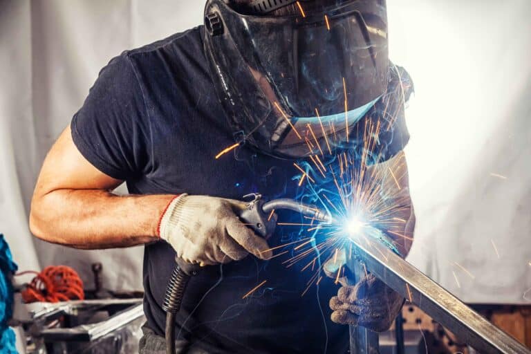 Technician welding commercial HVAC system components in workshop