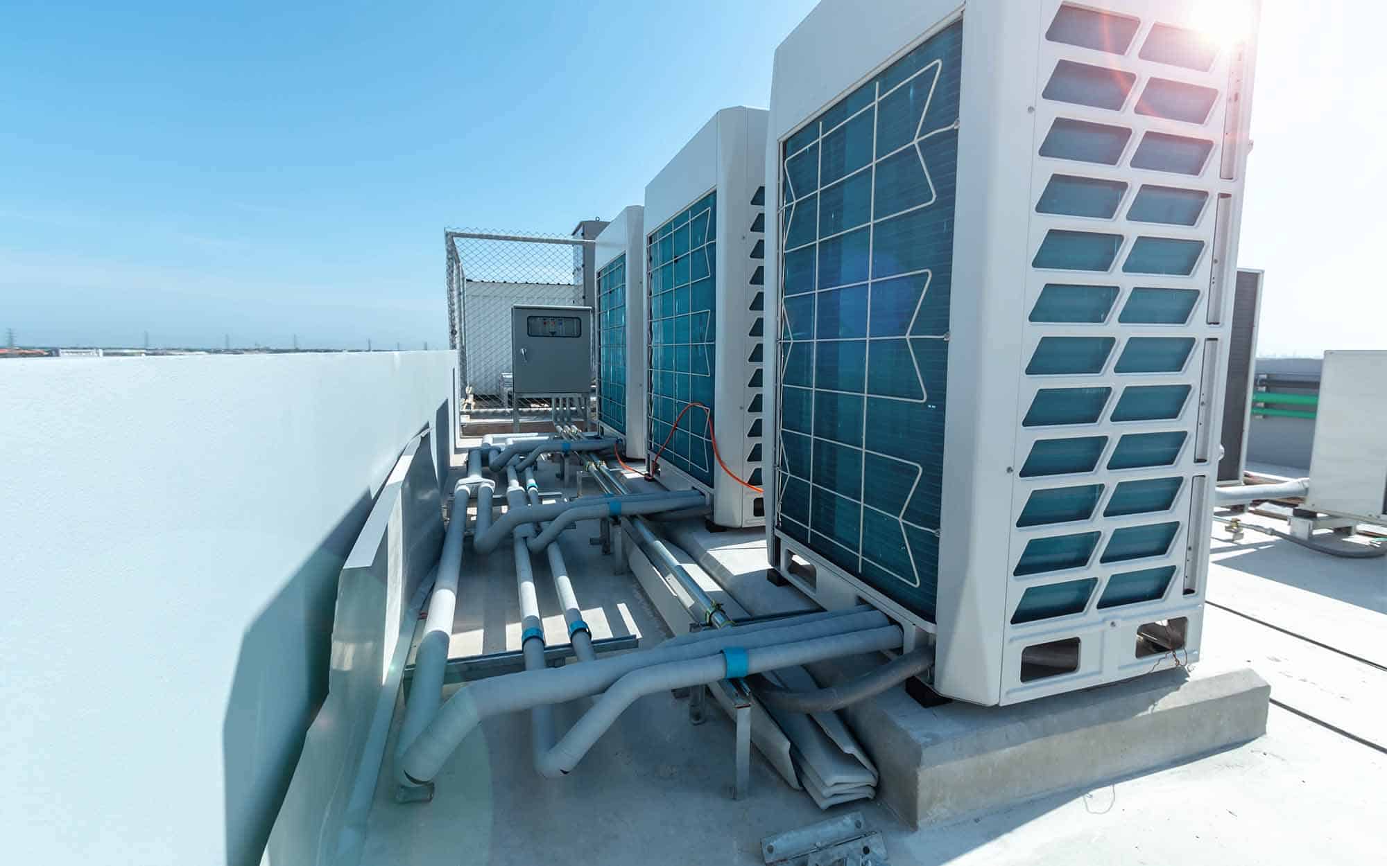 Commercial HVAC units installed on rooftop with solar panels and piping infrastructure