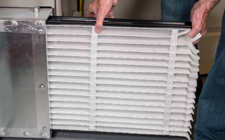 Hands holding dirty and clean HVAC air filters side by side for comparison