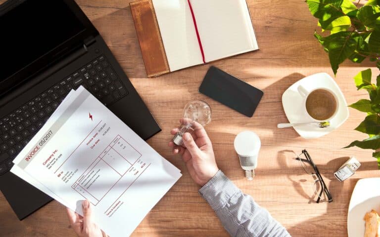 Professional workspace with laptop, invoice, coffee, and office supplies on wooden desk
