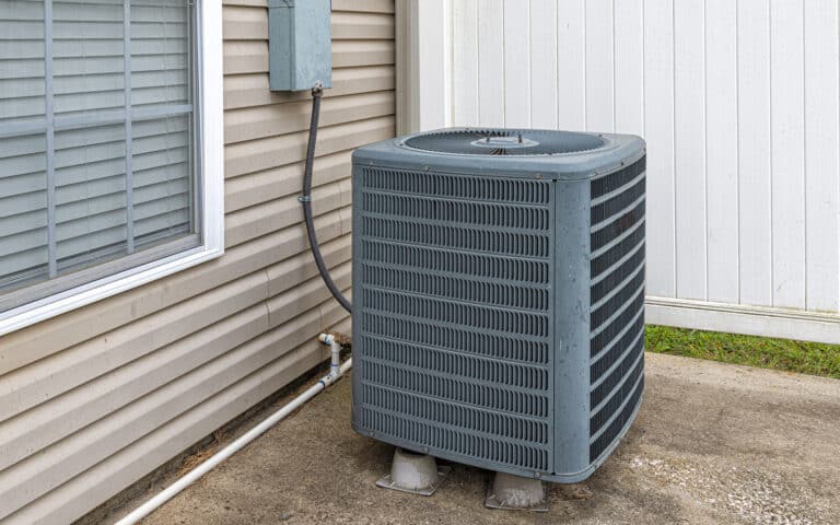 Outdoor air conditioning unit mounted beside house exterior wall