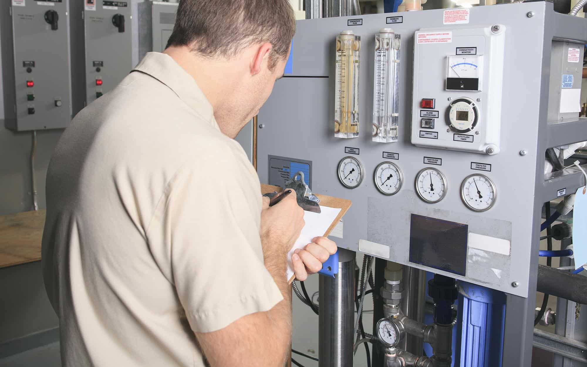 Technician inspecting industrial control panel with gauges and monitoring equipment