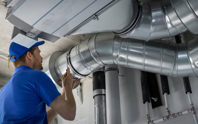 HVAC technician inspecting ductwork and metal piping system