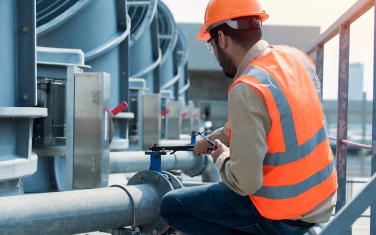 Construction worker operating valve on industrial rooftop equipment
