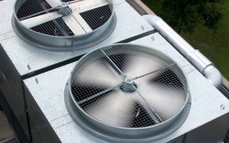 Rooftop HVAC condenser units with large circular fans and metal mesh grilles