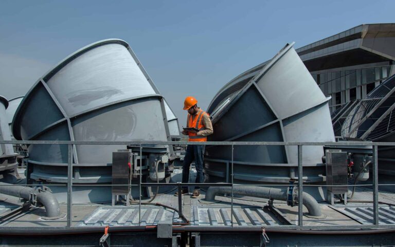 HVAC technician inspecting rooftop cooling equipment on commercial building