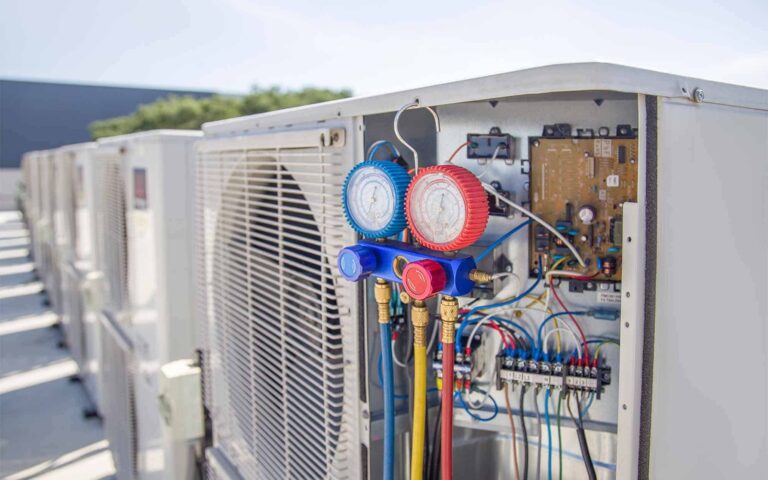 Commercial HVAC unit with diagnostic gauges and refrigerant lines on rooftop