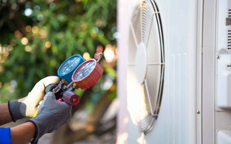 Technician holding pressure gauges during HVAC system maintenance check