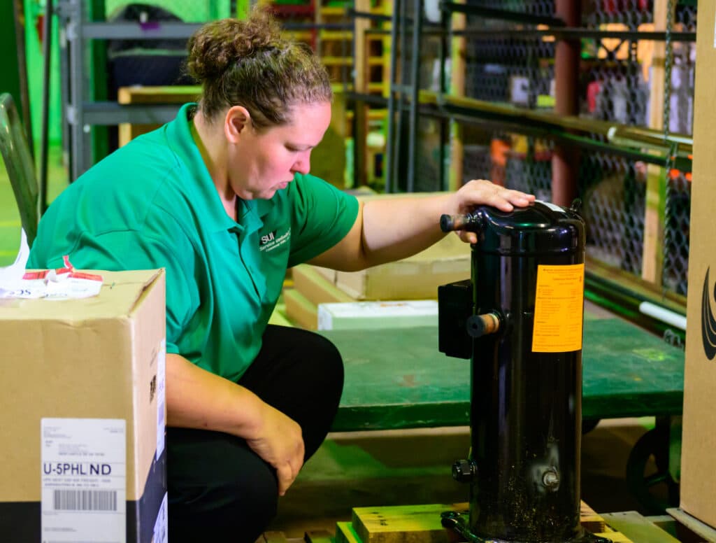 Service Unlimited employee in green shirt inspecting hydraulic equipment in warehouse