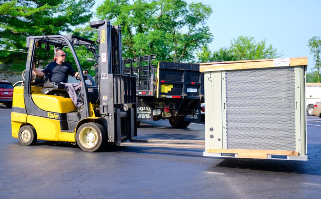Service Unlimited technician operating forklift to load HVAC equipment onto truck