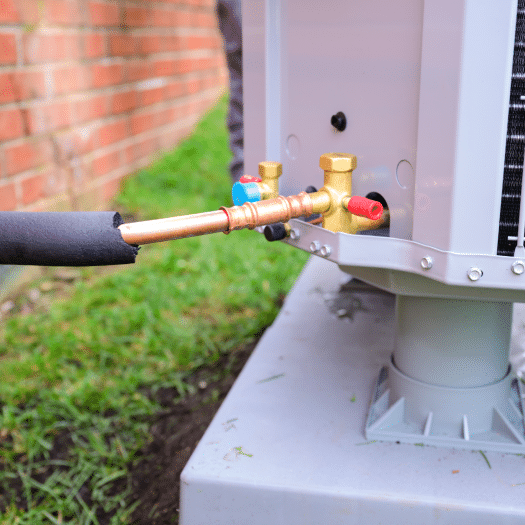 HVAC technician inspecting copper refrigerant lines on outdoor unit