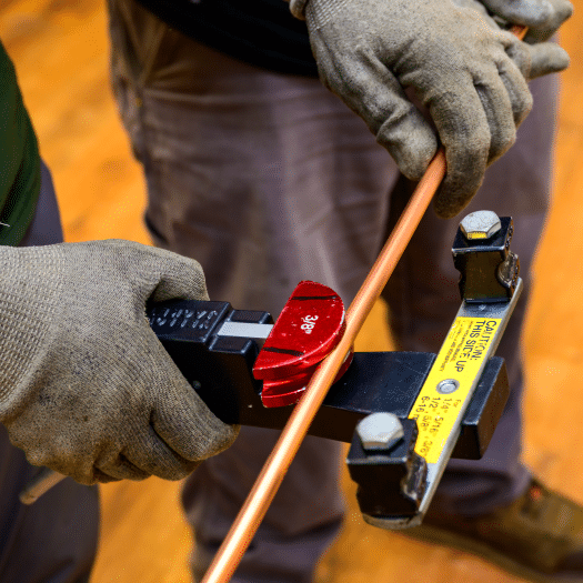 Technician's hands adjusting HVAC system component with tools