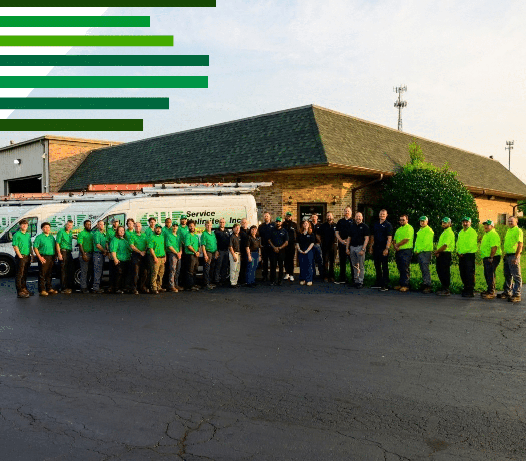 Photo of a group of service unlimited inc employees lined up smiling in front of the company building and a work truck